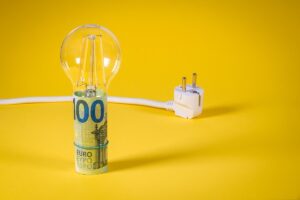 lampadina avvolta in una banconota con dietro un cavo elettrico