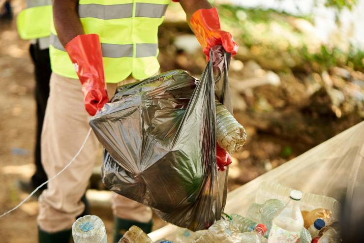 operatore ecologico con in mano un sacchetto pieno di rifiuti
