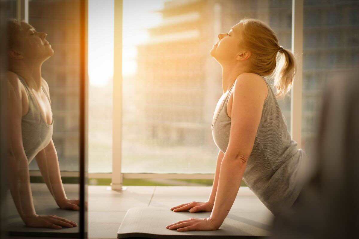 Donna rivolta al sole su un tappetino di ginnastica