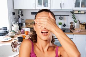 Cucina in disordine e donna con mano sugli occhi