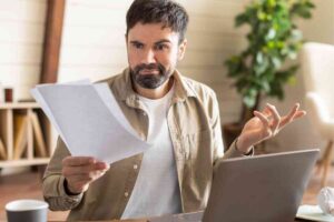 Uomo perplesso e foglio in mano