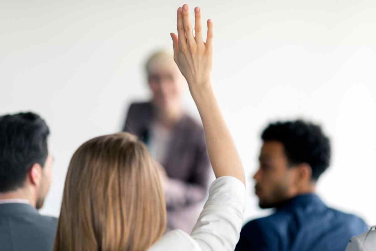Persona alza la mano ad una riunione