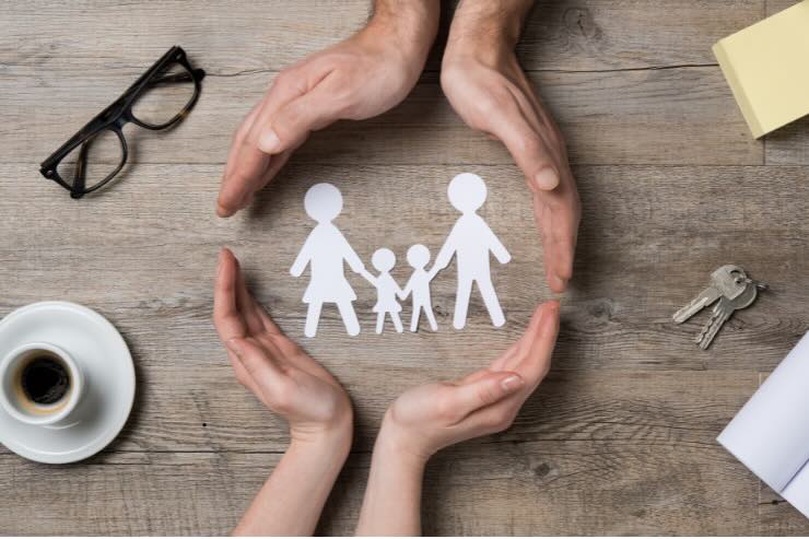 mani che incorniciano delle sagome di famiglia, occhiali e tazza di caffè