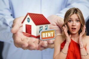 Mani tengono casetta con scritto "Rent", ragazza sconvolta in primo piano