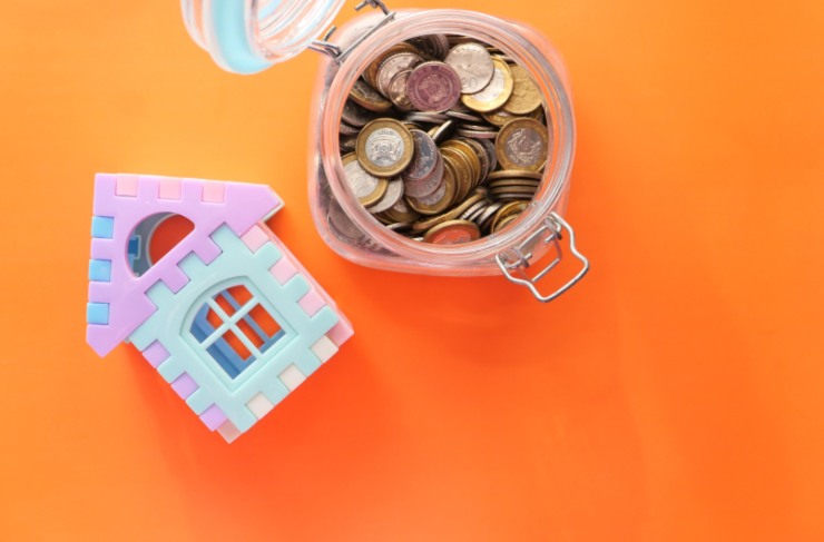 casetta in miniatura e contenitore pieno di monete di euro