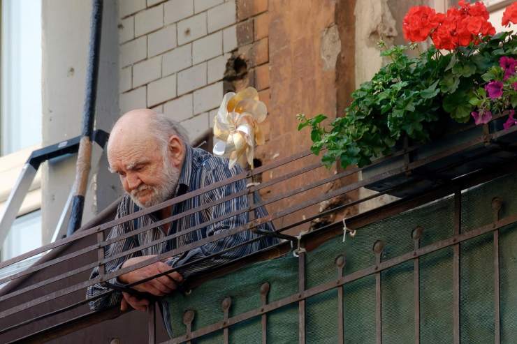 uomo anziano affacciato dal balcone