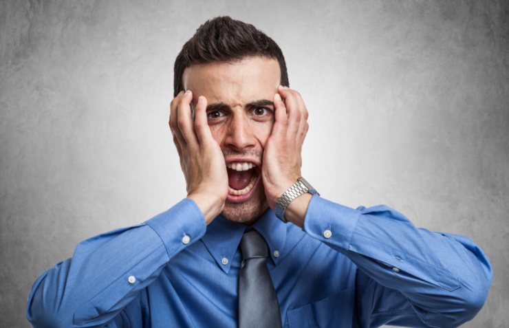 uomo che urla con le mani in faccia