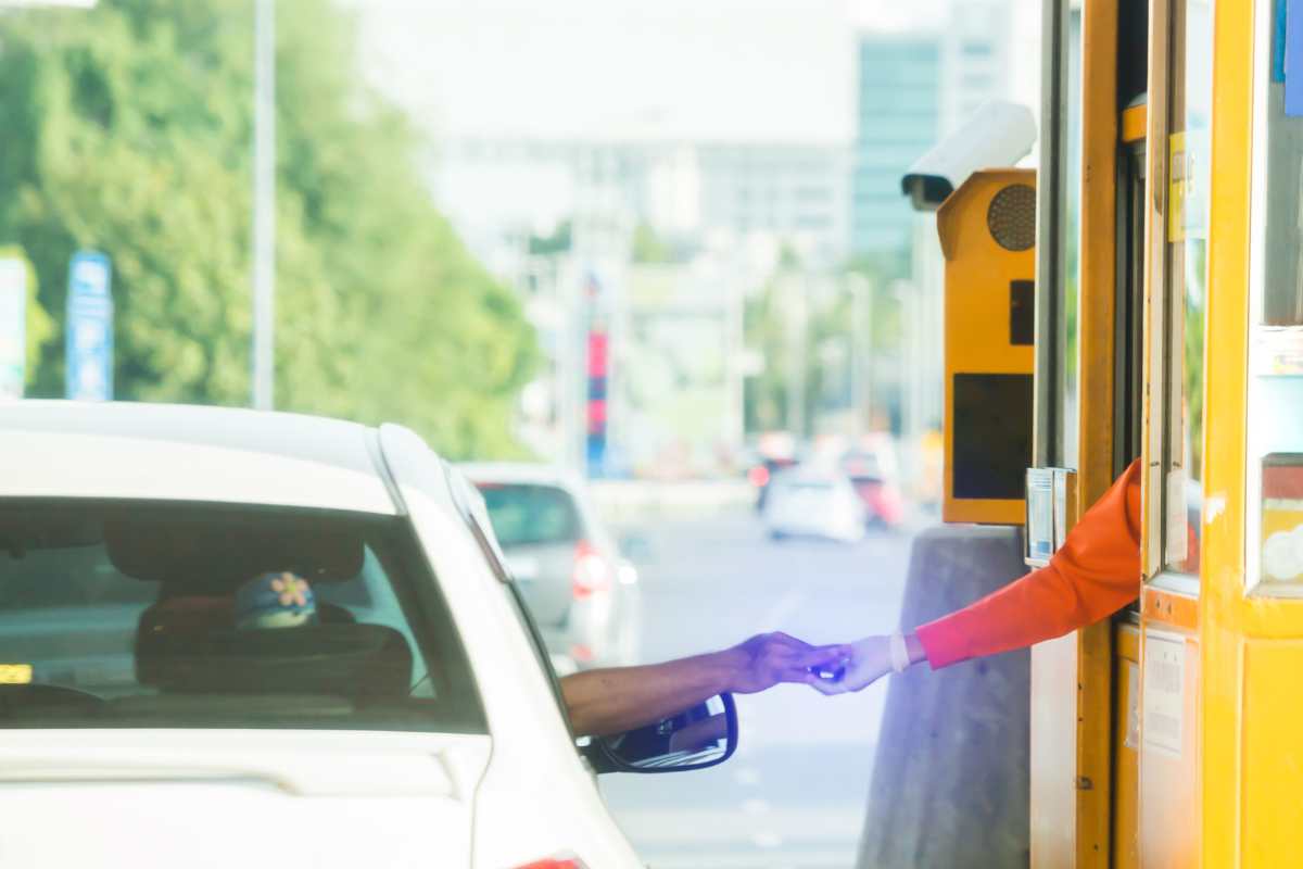 uomo che paga al casello autostradale