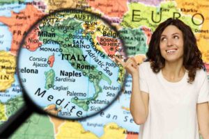 Cartina geografica con Italia ingrandita con lente di ingrandimento e ragazza sorridente che la indica