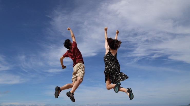uomo e donna che saltano in alto verso il cielo