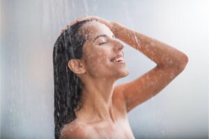 Ragazza sorridente sotto getto d'acqua della doccia