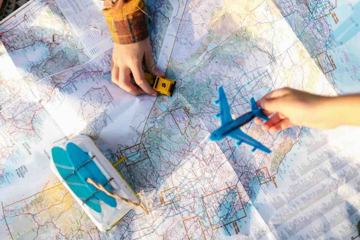 Mani con modellino auto su cartina, aeroplano e barchetta modellini