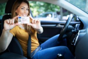 Ragazza in auto con cintura di sicurezza, sorridente mostra patente