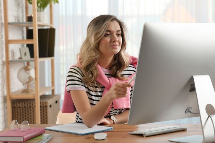 Ragazza al PC sorridente, maglia a righe, felpa rosa sulle spalle