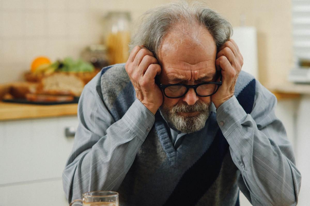 uomo seduto triste con le mani appoggiate ai lati della testa
