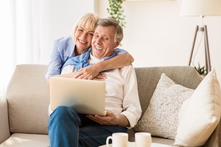 Donna e uomo abbracciati leggono qualcosa al PC