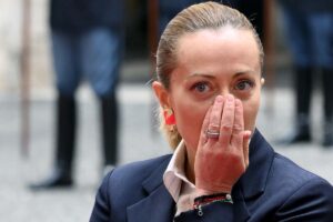 il premier giorgia meloni con una mano davanti alla bocca