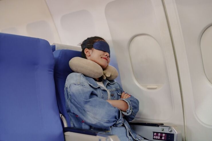 Ragazza seduta in aereo posto finestrino, dorme con cuscino