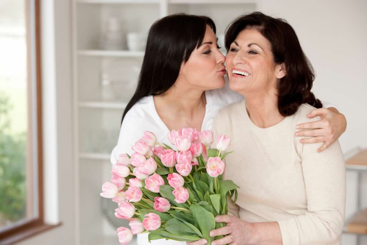 ragazza che abbraccia donna con fiori rosa