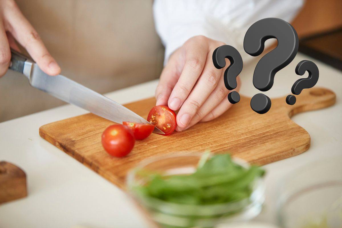 tagliere in legno ed una persona che taglie i pomodorini