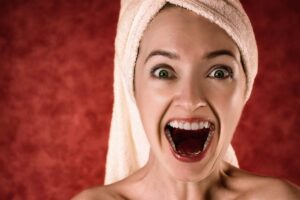 donna che ride con la bocca aperta e l'asciugamano in testa