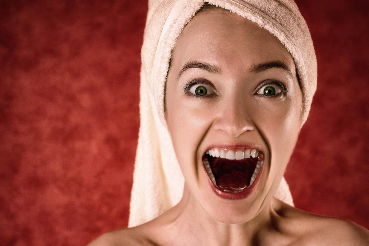 donna che ride con la bocca aperta e l'asciugamano in testa