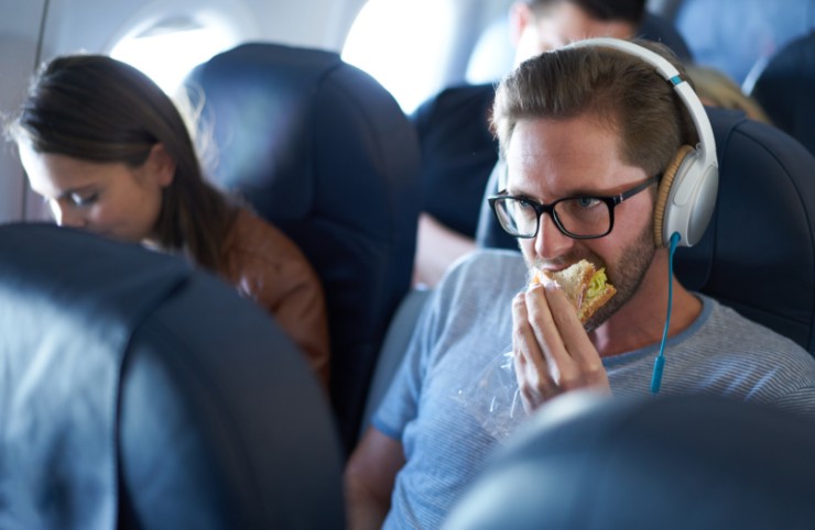 uomo che mangia un panino in aereo