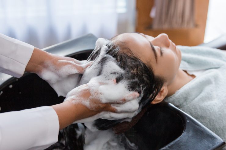 uomo che fa uno shampoo ad una cliente 