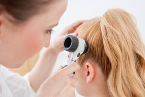 dermatologa che controlla i capelli di una paziente con una lente apposita