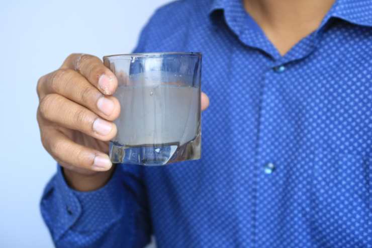 Una persona con un bicchiere in mano di acqua sporca