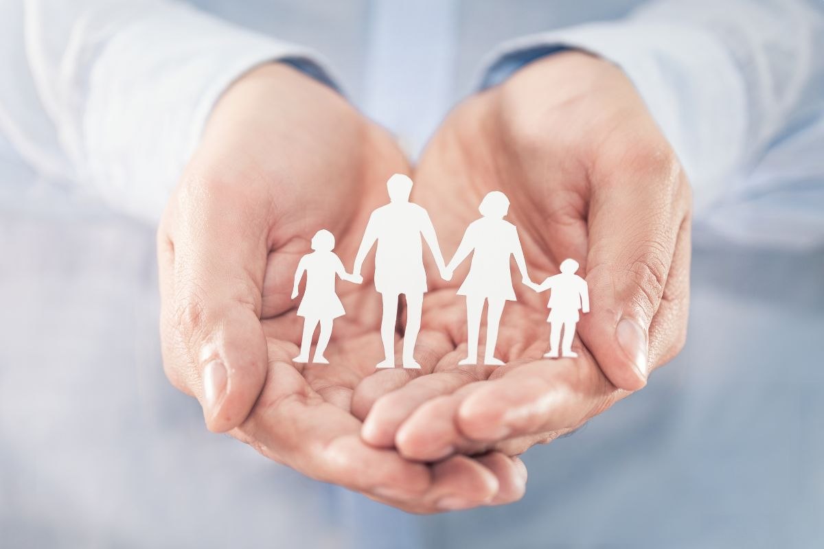 due mani sovrapposte che tengono una famiglia fatta di carta