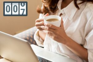 una persona che sta seduta con il computer portatile sulle gambe che beve un caffè, ed in alto a sinistra un contatore