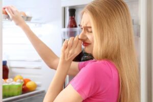 una ragazza che sente un cattivo odore dal frigo