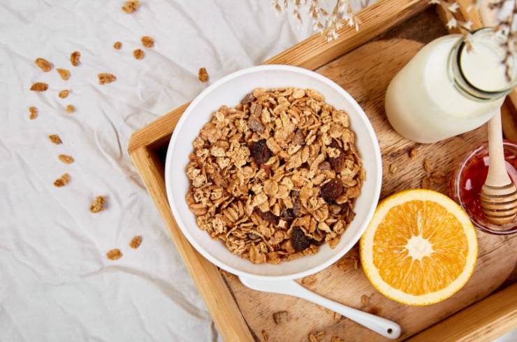 tazza di cereali con accanto mezza rancia del latte e del miele