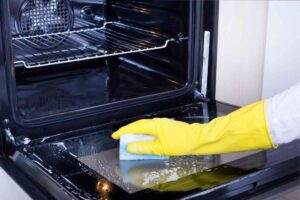 mano con guanto e spugna per pulire il forno