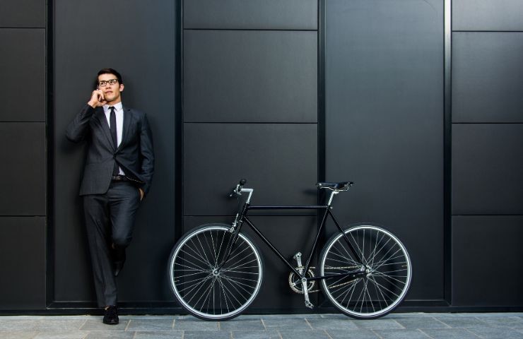un uomo che parla al telefono ed ha una bicicletta vicino
