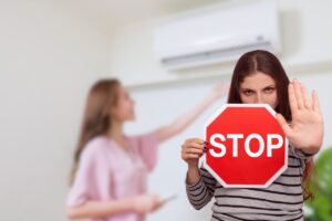 donna che accende condizionatore e un'altra con cartello stop