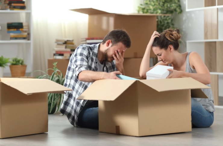 uomo e donna seduti sul pavimento che piangono circondati da scatoloni
