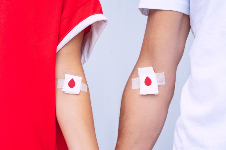 il braccio di una donna a destra e di un uomo a destra entrambi con un cerotto con una gocce di sangue sul braccio