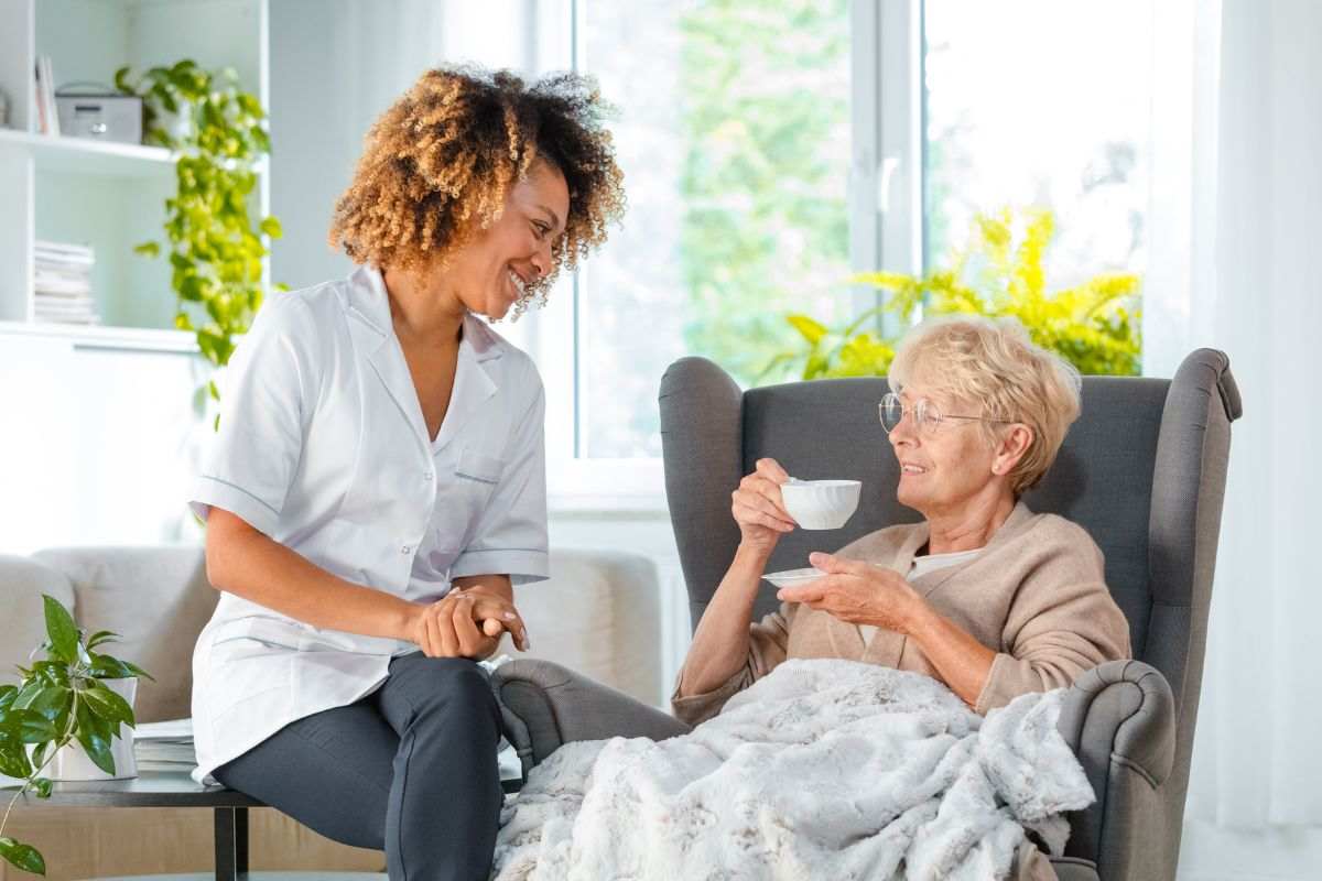 una persona aiuta un anziano seduto in poltrona