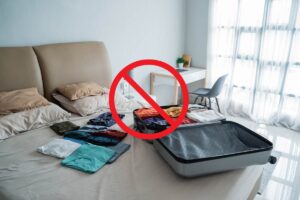 valigia disfatta sul letto con davanti un segnale di divieto