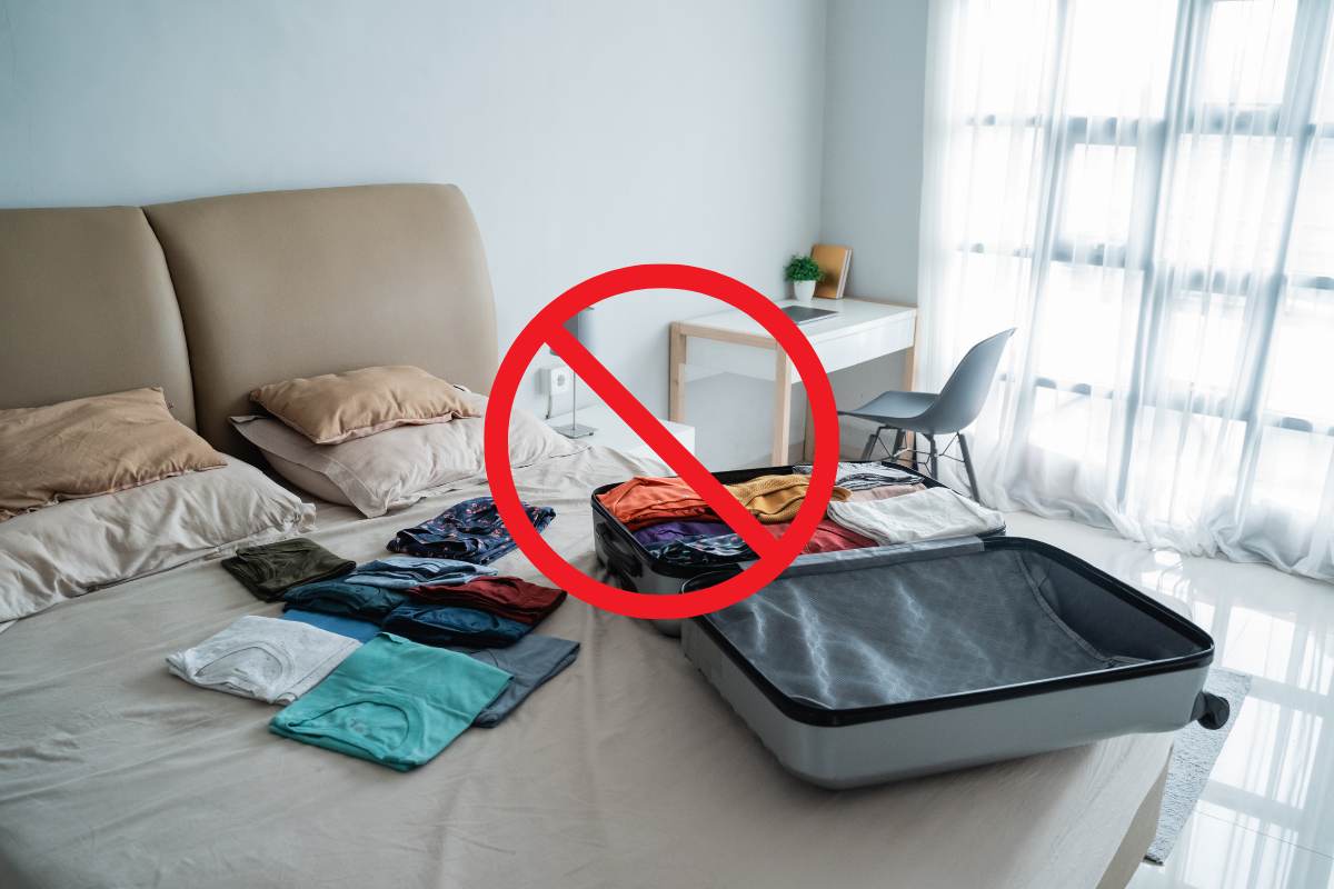valigia disfatta sul letto con davanti un segnale di divieto