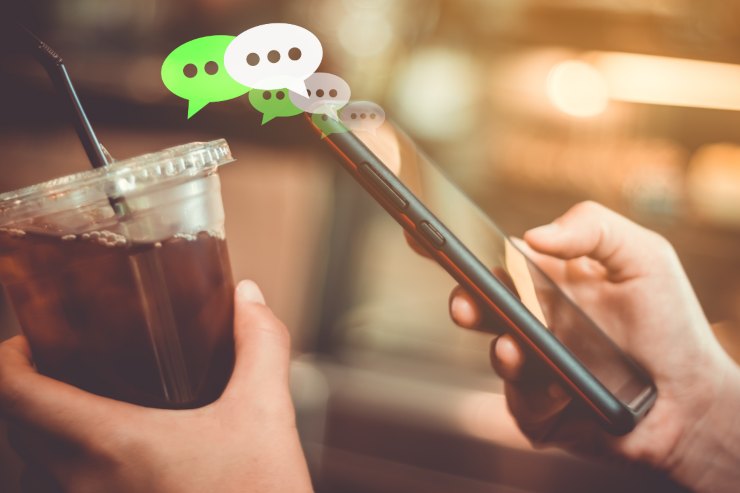 persona che risponde a dei messaggi mentre ha nell'altra mano un bicchiere con una bibita
