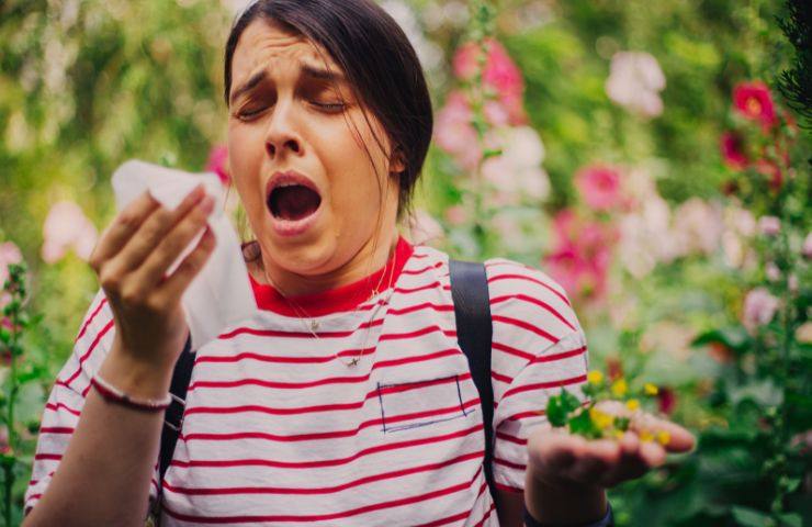una persona allergica che starnutisce