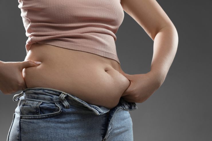 donna un pò robusta con pantaloni slacciati che si tocca la pancia