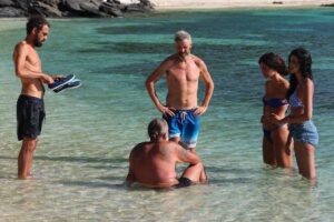 i naufraghi della trasmissione televisiva "L'isola dei famosi" che stanno in riva al mare e parlano tra loro