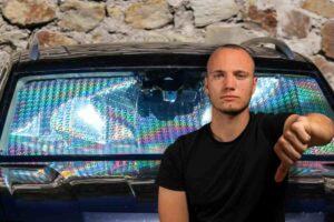 Uomo con pollice in giù, sul retro auto con parasole