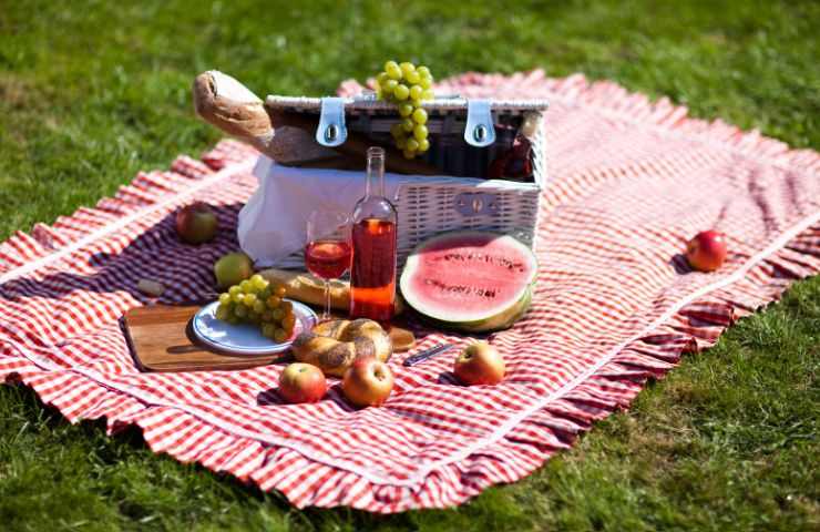 una tovaglia per terra con un cesto sopra con delle frutta