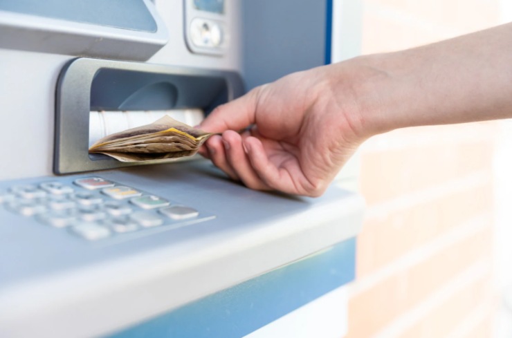 persona che ritira delle banconote da uno sportello automatico