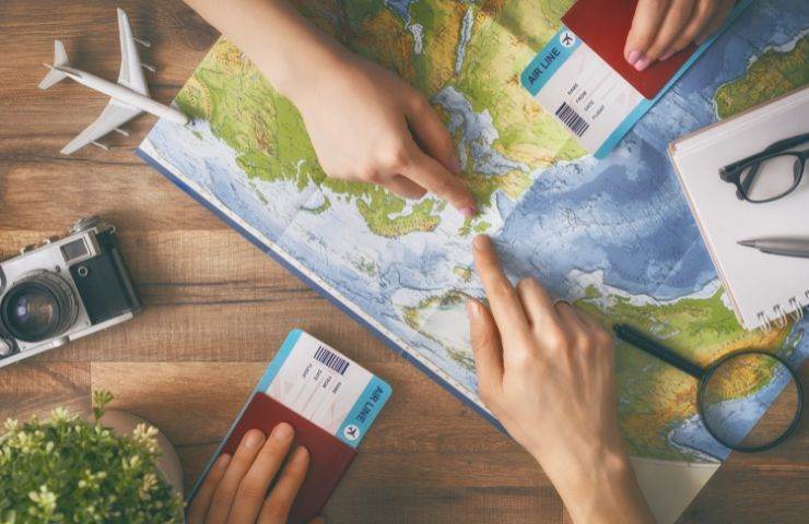 una cartina geografica su un tavolo e delle persone attorno che hanno i passaporti